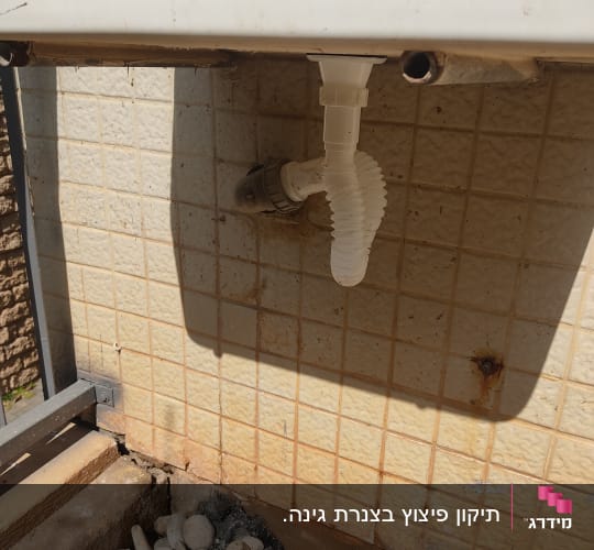 צינור פלסטיק לבן מחובר לקיר אריחים